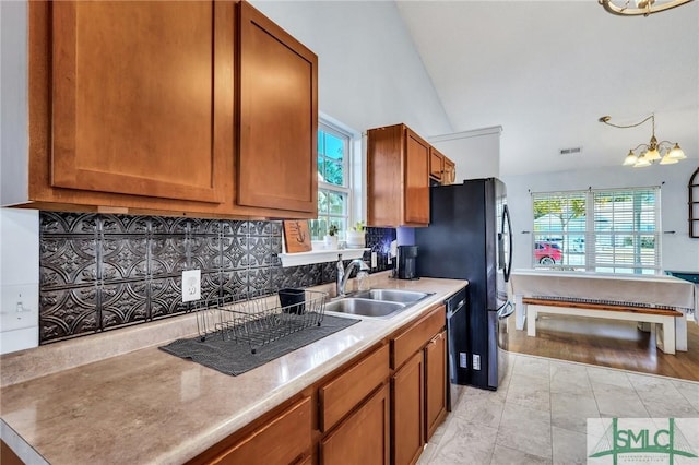 kitchen featuring vaulted ceiling, dishwasher, pendant lighting, sink, and an inviting chandelier