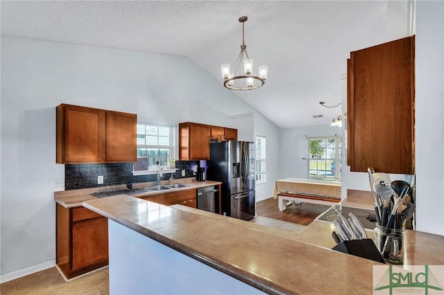 kitchen with decorative light fixtures, vaulted ceiling, appliances with stainless steel finishes, and a wealth of natural light