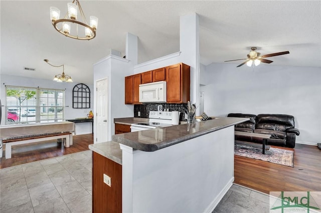 kitchen with hanging light fixtures, kitchen peninsula, vaulted ceiling, and white appliances