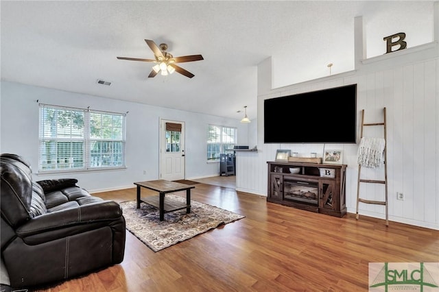 living room with ceiling fan, wood-type flooring, a wealth of natural light, and vaulted ceiling