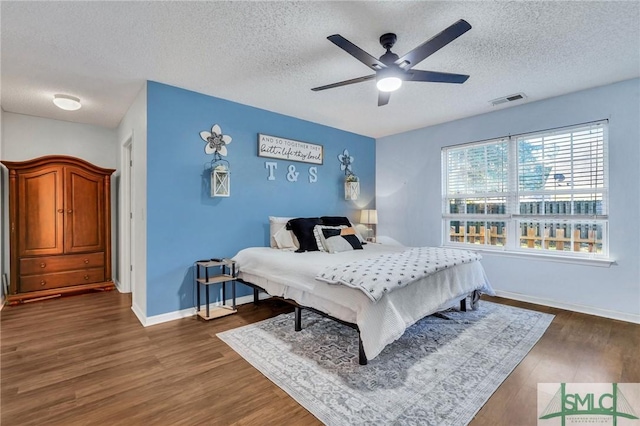 bedroom featuring ceiling fan, dark wood-type flooring, and a textured ceiling