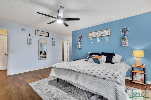 bedroom with ceiling fan, dark wood-type flooring, and a textured ceiling