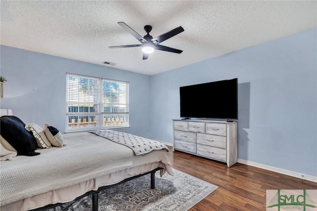 bedroom with ceiling fan, dark wood-type flooring, and a textured ceiling