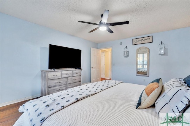 bedroom with a textured ceiling, ceiling fan, and hardwood / wood-style flooring