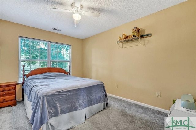 bedroom with ceiling fan, light colored carpet, and a textured ceiling