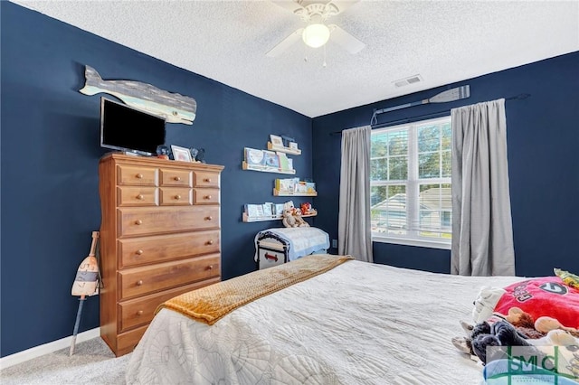 carpeted bedroom featuring ceiling fan and a textured ceiling