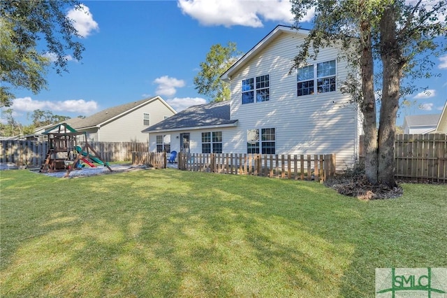 rear view of property featuring a yard and a playground