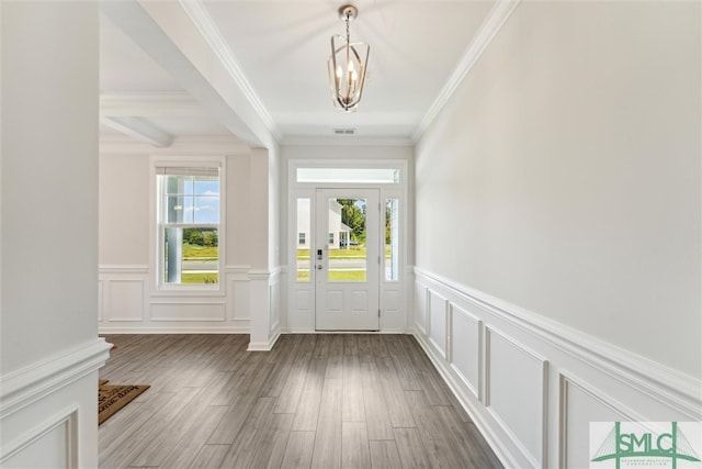 foyer entrance featuring a chandelier, hardwood / wood-style floors, crown molding, and beam ceiling