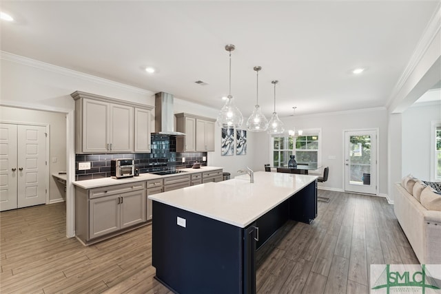 kitchen featuring pendant lighting, a spacious island, hardwood / wood-style flooring, and wall chimney exhaust hood