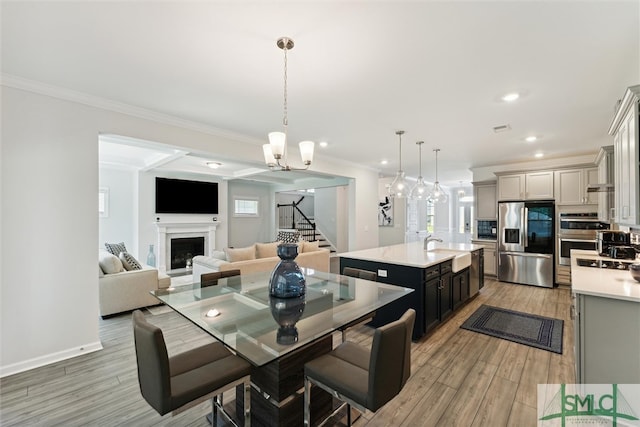 dining room with a chandelier, wood-type flooring, crown molding, and sink