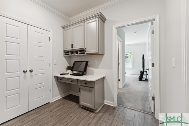 office space with ornamental molding, light wood-type flooring, and built in desk