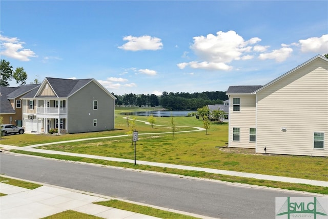 view of side of home with a balcony, a yard, and a water view