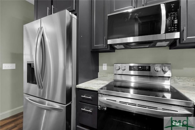 kitchen featuring dark hardwood / wood-style flooring, light stone countertops, and appliances with stainless steel finishes