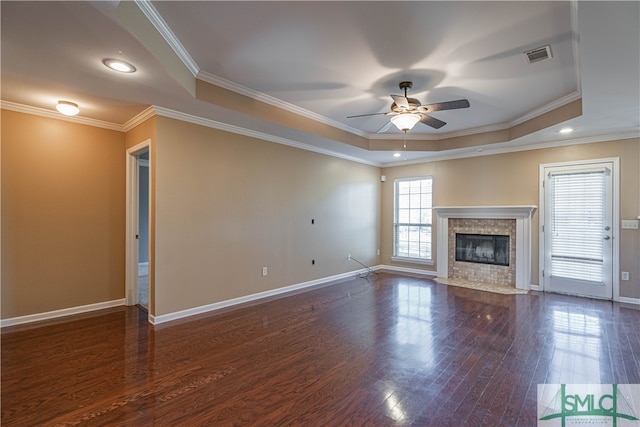 unfurnished living room featuring crown molding, dark hardwood / wood-style floors, ceiling fan, a fireplace, and a tray ceiling