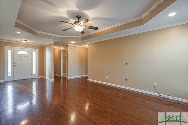 interior space with a tray ceiling, ceiling fan, dark wood-type flooring, and ornamental molding