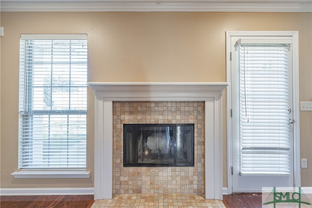 room details featuring a tile fireplace, ornamental molding, and hardwood / wood-style flooring