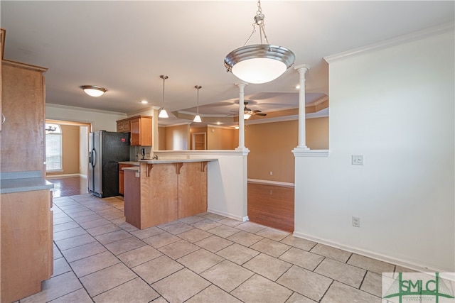 kitchen with a kitchen breakfast bar, ornamental molding, kitchen peninsula, stainless steel refrigerator, and decorative columns