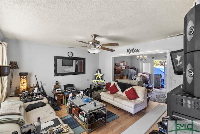 living room featuring ceiling fan with notable chandelier, wood-type flooring, and a textured ceiling