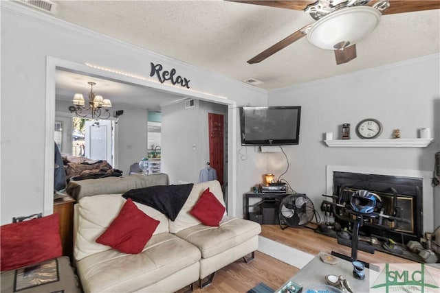 living room featuring light hardwood / wood-style flooring, ceiling fan with notable chandelier, a textured ceiling, and ornamental molding