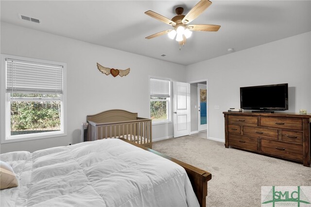 bedroom featuring ceiling fan, light carpet, and multiple windows