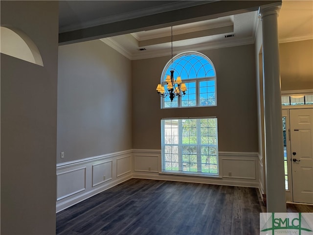 entryway with a raised ceiling, ornamental molding, dark wood-type flooring, and an inviting chandelier