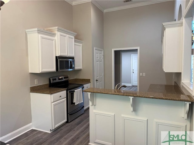 kitchen with a breakfast bar, dark hardwood / wood-style floors, kitchen peninsula, stainless steel appliances, and white cabinets