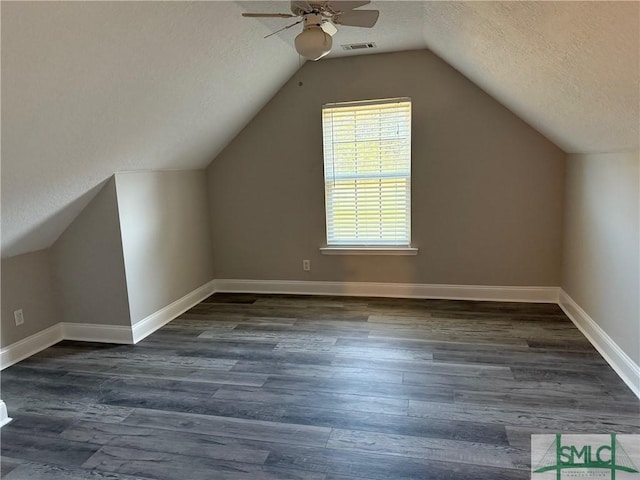 additional living space with dark hardwood / wood-style flooring, ceiling fan, vaulted ceiling, and a textured ceiling