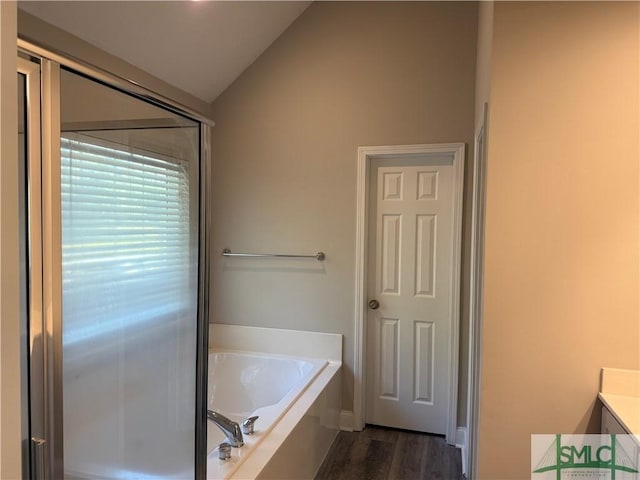 bathroom with hardwood / wood-style flooring, a tub to relax in, lofted ceiling, and vanity