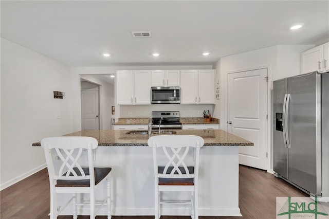 kitchen featuring white cabinetry, a kitchen island with sink, a breakfast bar, and stainless steel appliances