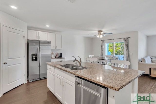 kitchen featuring dark hardwood / wood-style flooring, stainless steel appliances, sink, white cabinets, and an island with sink