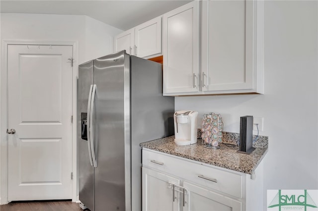 kitchen with dark hardwood / wood-style floors, stainless steel fridge, light stone counters, and white cabinetry