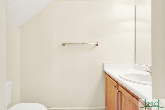 bathroom with vanity, toilet, and a textured ceiling