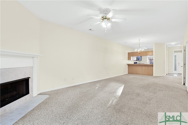 unfurnished living room with light carpet, ceiling fan with notable chandelier, and a fireplace