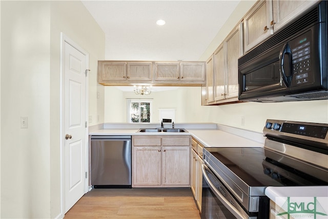 kitchen featuring light wood-type flooring, stainless steel appliances, light brown cabinetry, and a chandelier