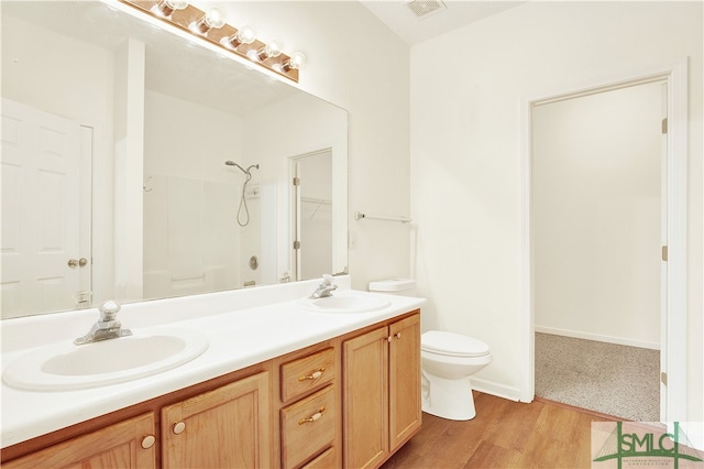 bathroom featuring hardwood / wood-style flooring, vanity, toilet, and walk in shower