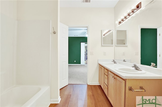 bathroom with hardwood / wood-style floors, vanity, and  shower combination