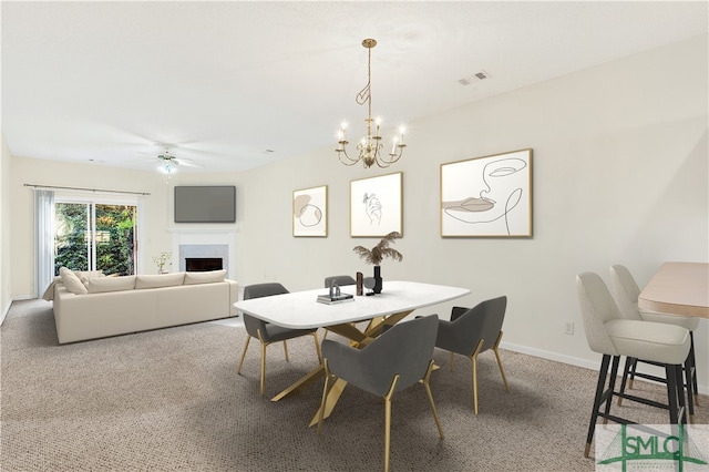 carpeted dining room with ceiling fan with notable chandelier