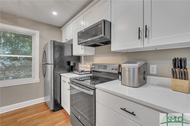 kitchen featuring light stone countertops, white cabinetry, light hardwood / wood-style flooring, and stainless steel appliances