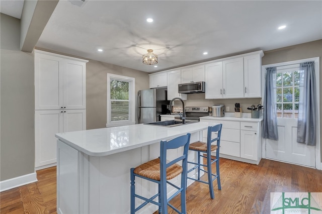 kitchen featuring appliances with stainless steel finishes, white cabinetry, a kitchen island with sink, and plenty of natural light