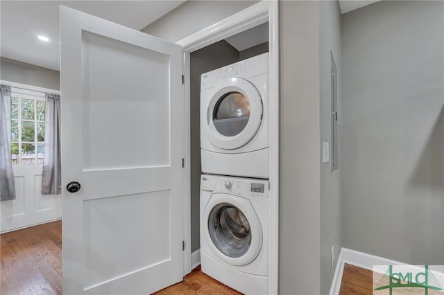 laundry area featuring hardwood / wood-style floors and stacked washer and clothes dryer