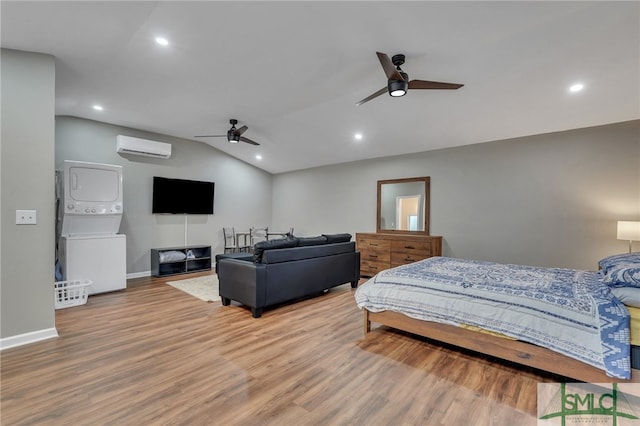 bedroom featuring ceiling fan, stacked washer / dryer, a wall mounted AC, hardwood / wood-style floors, and vaulted ceiling