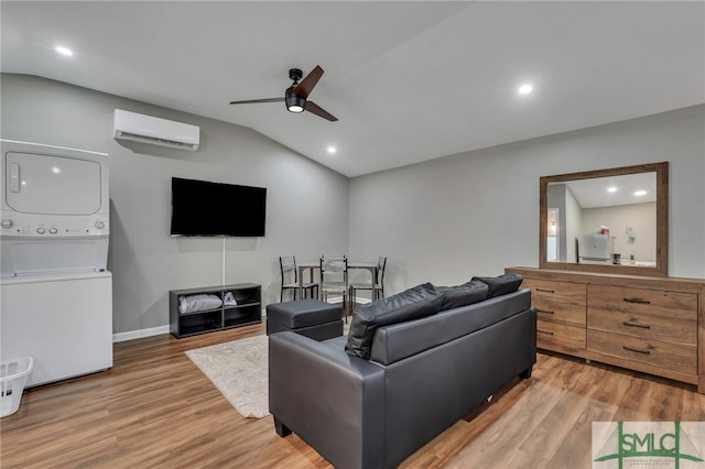 living room with hardwood / wood-style floors, lofted ceiling, a wall unit AC, and stacked washer and clothes dryer