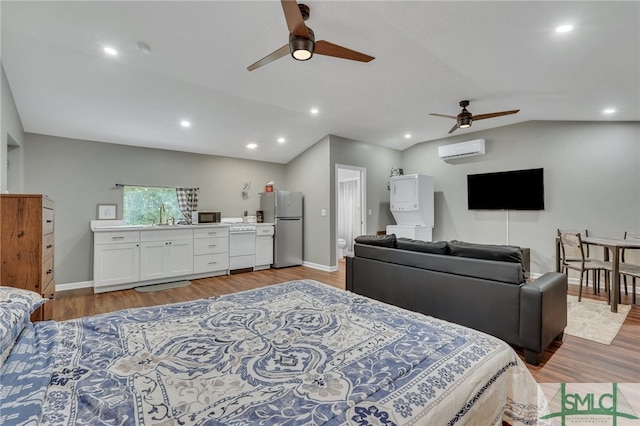 bedroom featuring hardwood / wood-style floors, sink, vaulted ceiling, stainless steel refrigerator, and a wall unit AC