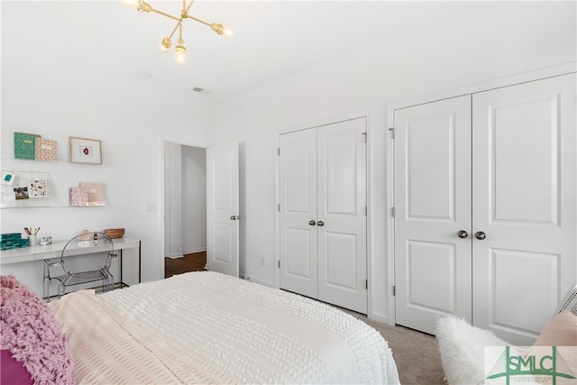 bedroom featuring a chandelier and multiple closets