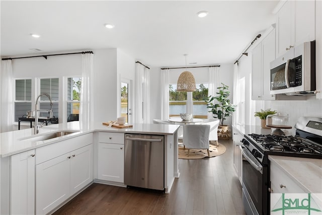 kitchen with dark wood-type flooring, a sink, stainless steel appliances, light countertops, and backsplash