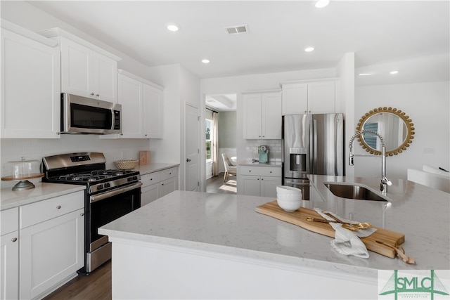 kitchen with appliances with stainless steel finishes, backsplash, a sink, and white cabinetry