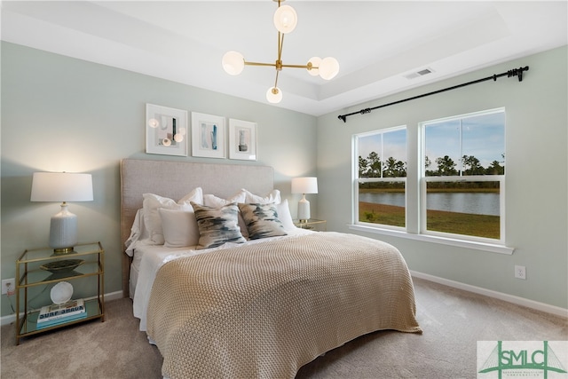 bedroom with a tray ceiling, baseboards, a notable chandelier, and carpet