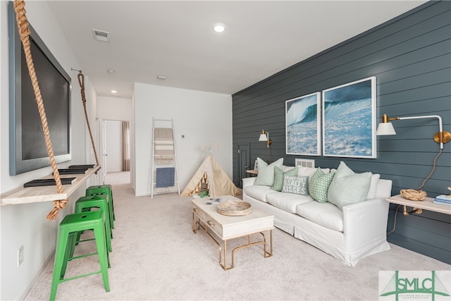 carpeted living area with an accent wall, visible vents, and recessed lighting