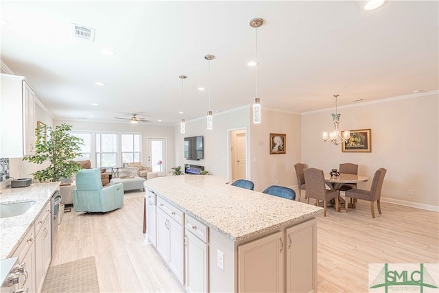 kitchen with light stone counters, decorative light fixtures, a center island, and white cabinets