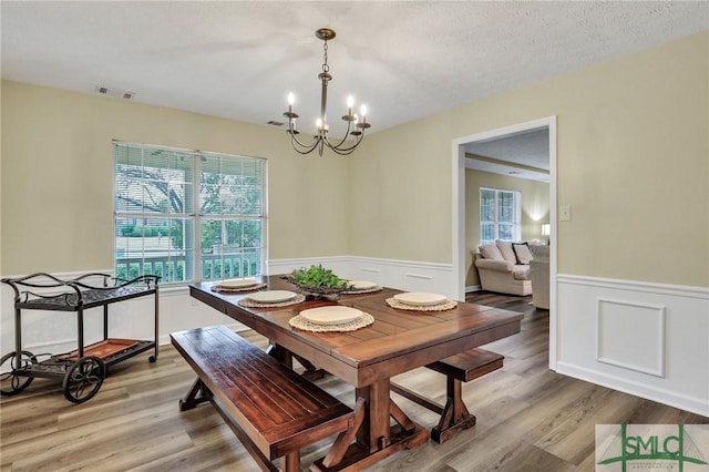 dining room with hardwood / wood-style floors, a chandelier, and a textured ceiling